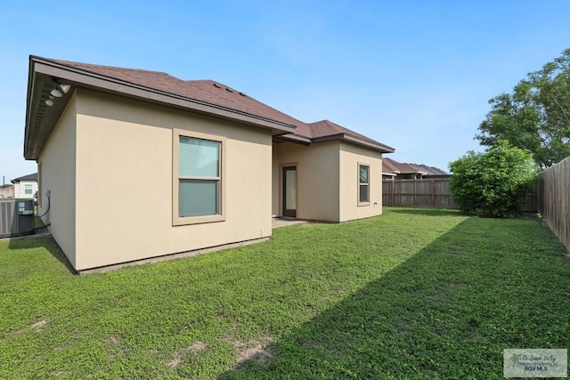rear view of property with central air condition unit, a yard, stucco siding, and a fenced backyard