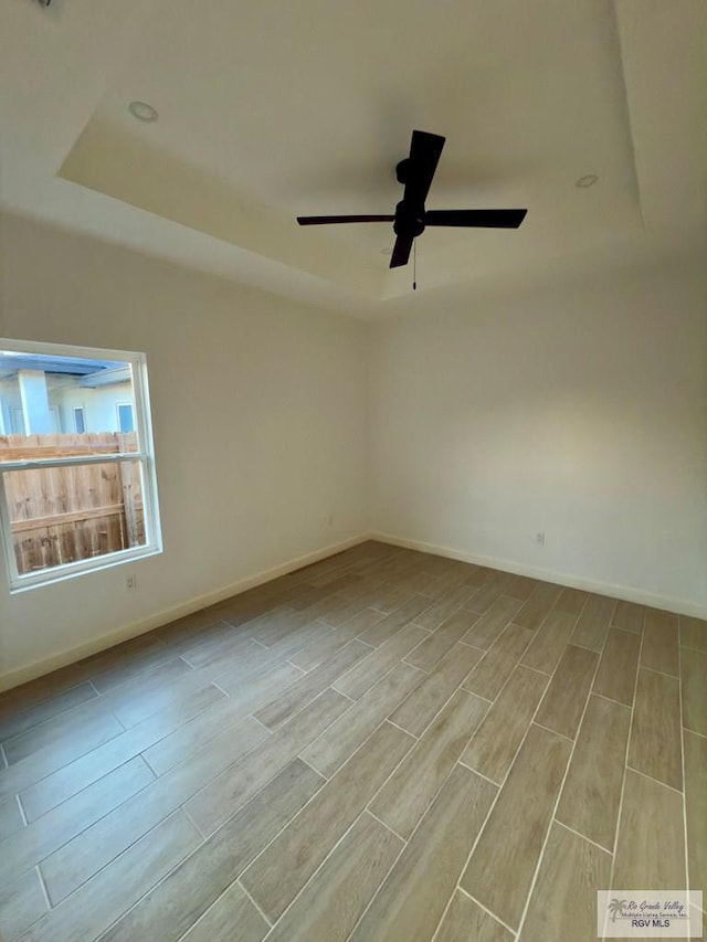 7533 Hana Dr, Brownsville, TX 78520 - empty room featuring a tray ceiling, wood tiled floors, ceiling fan, and baseboards