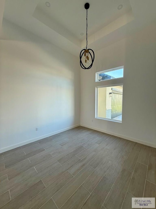 7533 Hana Dr, Brownsville, TX 78520 - unfurnished room with a tray ceiling, dark wood-style floors, a chandelier, and baseboards