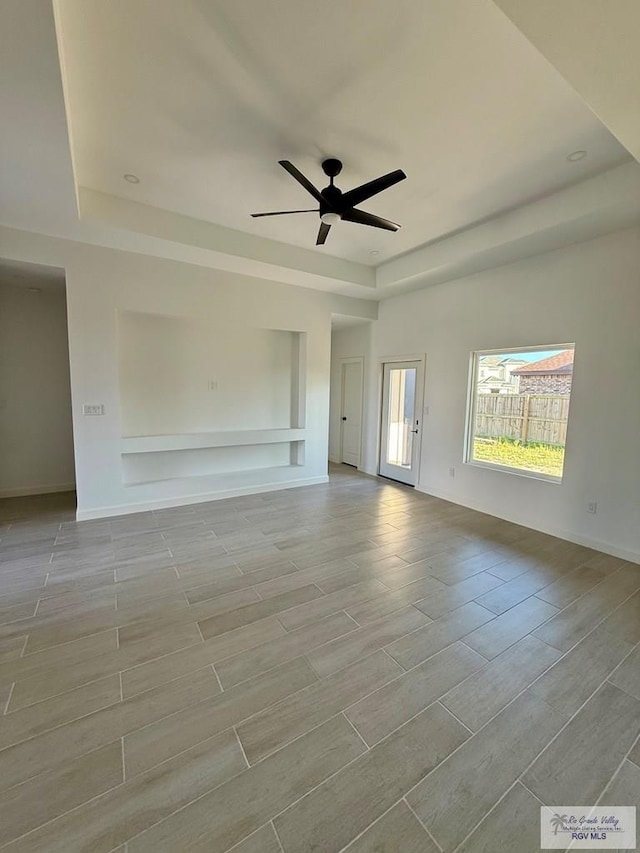 7533 Hana Dr, Brownsville, TX 78520 - empty room with a tray ceiling, wood tiled floors, ceiling fan, and baseboards