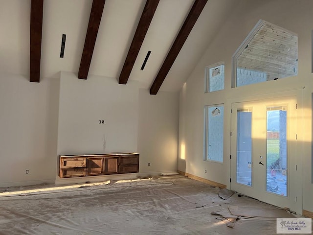 unfurnished living room with beam ceiling, high vaulted ceiling, and french doors