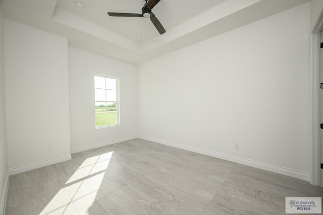 spare room with a raised ceiling and ceiling fan