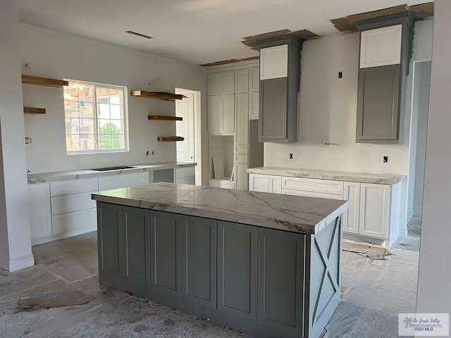 kitchen with black electric stovetop, light stone counters, gray cabinetry, white cabinets, and a kitchen island