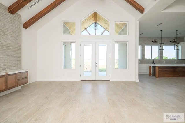 foyer entrance with high vaulted ceiling, french doors, beam ceiling, light hardwood / wood-style floors, and brick wall