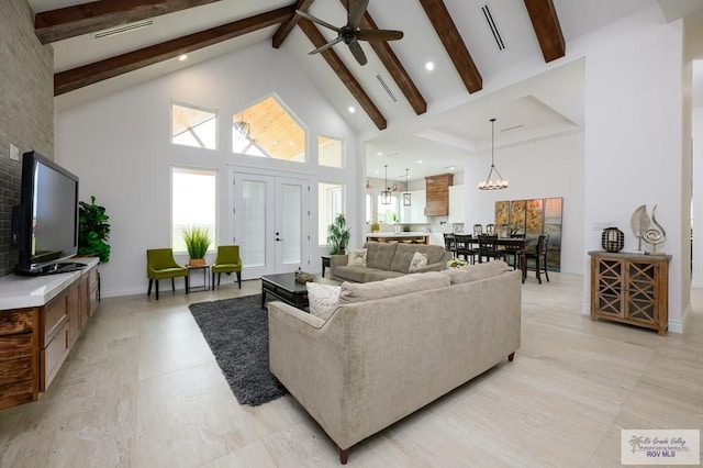 living room with ceiling fan with notable chandelier, beam ceiling, high vaulted ceiling, and french doors