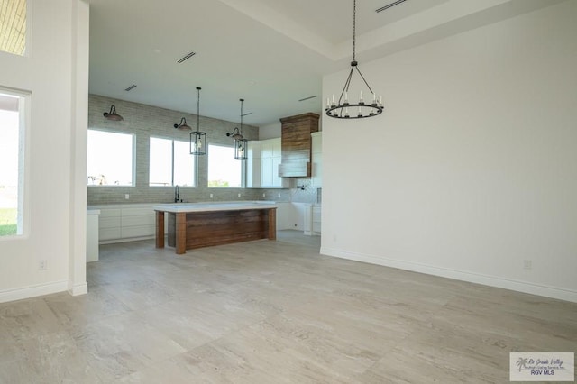 kitchen with backsplash, a wealth of natural light, white cabinetry, and pendant lighting