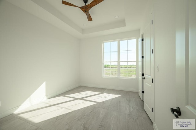 unfurnished room featuring a tray ceiling and ceiling fan