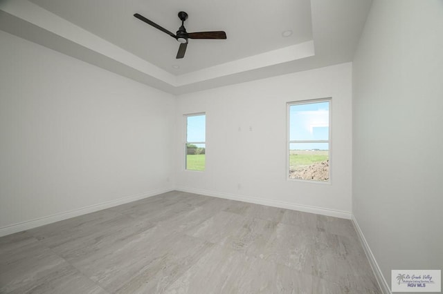 empty room featuring ceiling fan and a tray ceiling