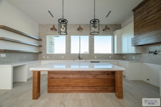 kitchen featuring white cabinets, decorative light fixtures, a center island, and tasteful backsplash