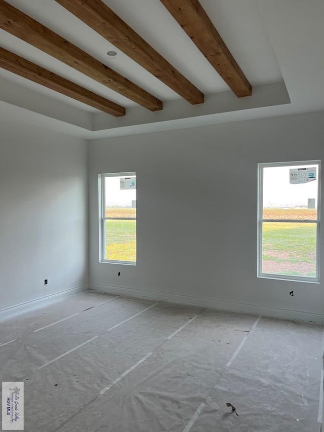 unfurnished room with beamed ceiling