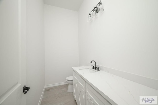 bathroom with vanity, wood-type flooring, and toilet