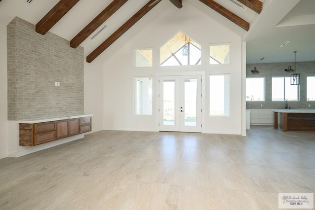 unfurnished living room with a wealth of natural light, beam ceiling, high vaulted ceiling, and french doors