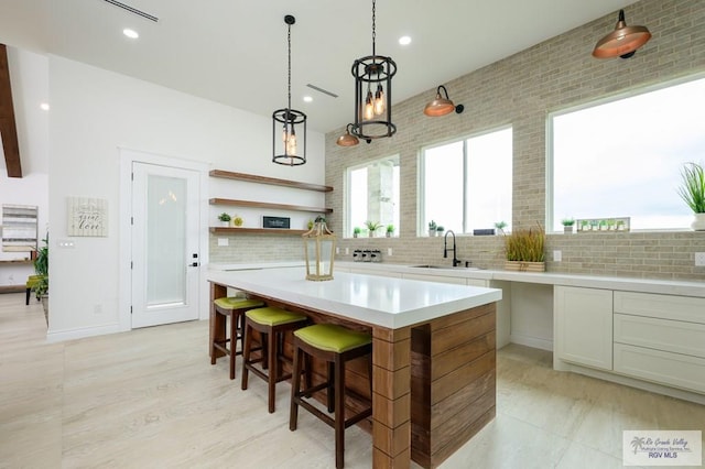 kitchen featuring decorative backsplash, a kitchen bar, sink, a center island, and hanging light fixtures