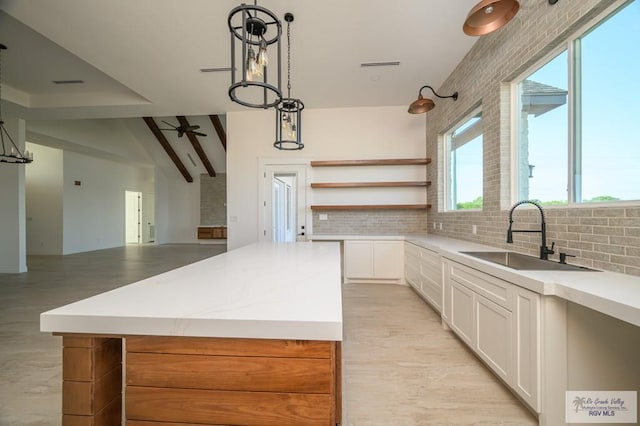 kitchen featuring a center island, sink, hanging light fixtures, decorative backsplash, and white cabinets