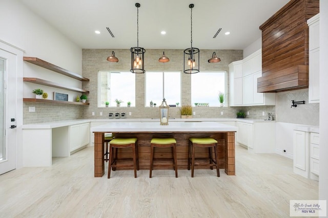 kitchen with a kitchen bar, a center island, tasteful backsplash, and white cabinetry