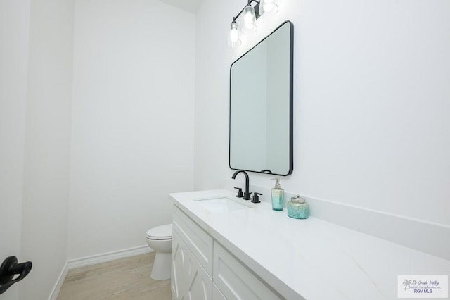 bathroom featuring wood-type flooring, vanity, and toilet