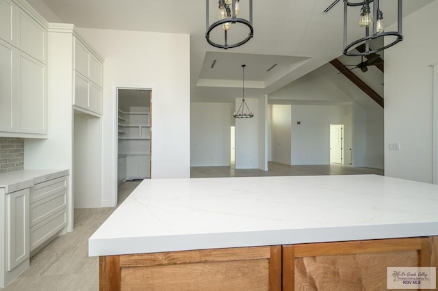 kitchen featuring backsplash, white cabinetry, a kitchen island, and pendant lighting