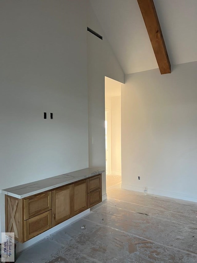 empty room featuring beam ceiling and high vaulted ceiling