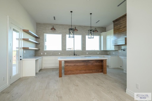 kitchen with backsplash, sink, light hardwood / wood-style flooring, white cabinets, and a kitchen island