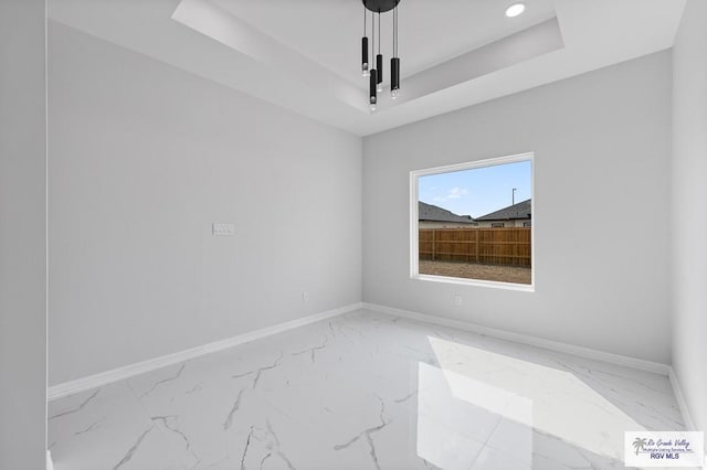 unfurnished room featuring baseboards, a raised ceiling, and marble finish floor