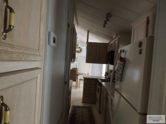 kitchen featuring vaulted ceiling, light brown cabinetry, rail lighting, and white appliances