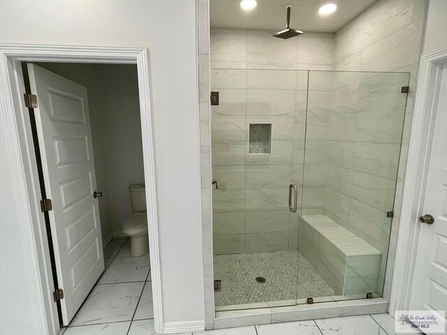 bathroom featuring a shower with shower door and toilet