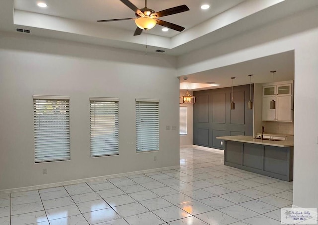 kitchen with pendant lighting, a towering ceiling, a raised ceiling, and ceiling fan