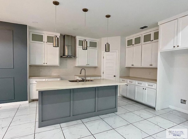 kitchen featuring sink, white cabinets, hanging light fixtures, and wall chimney range hood