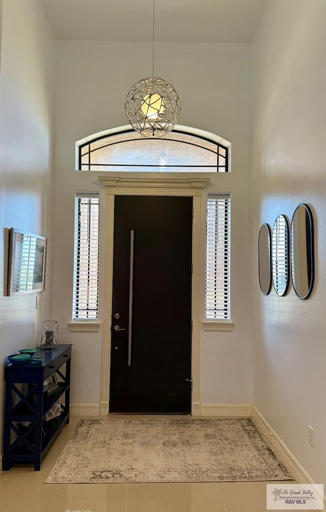 tiled entrance foyer with a high ceiling and baseboards