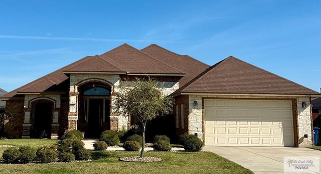 french country inspired facade with a front yard, stone siding, an attached garage, and concrete driveway