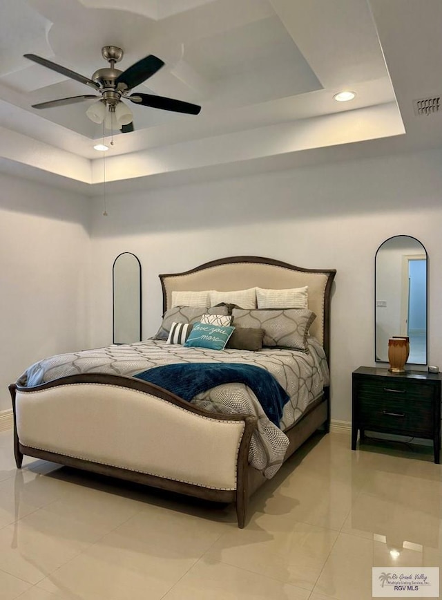 tiled bedroom featuring ceiling fan and a tray ceiling