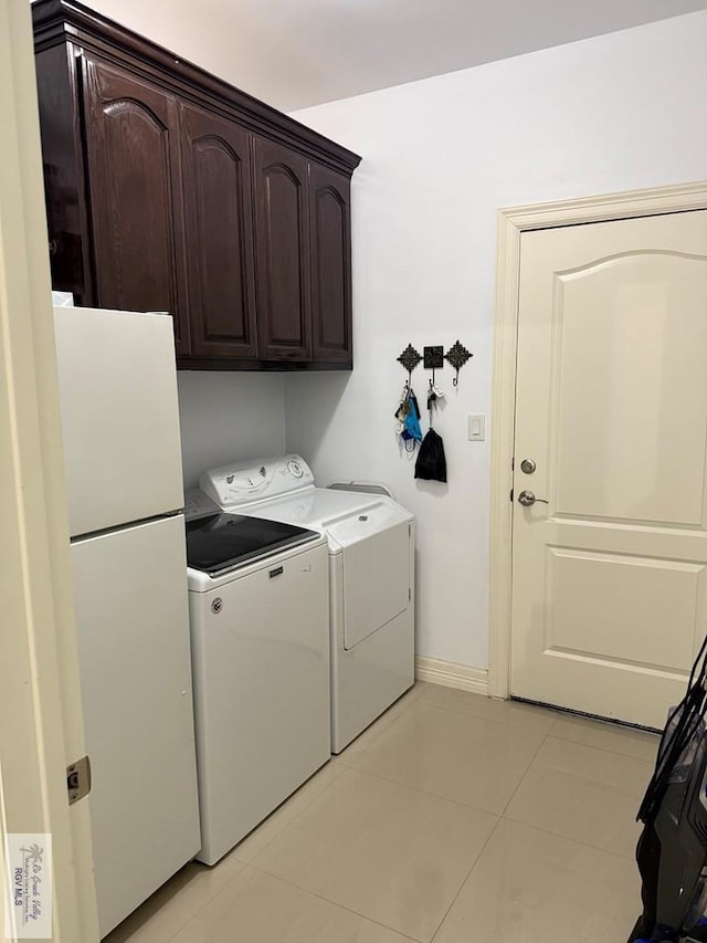 clothes washing area with cabinets, light tile patterned floors, and washer and clothes dryer