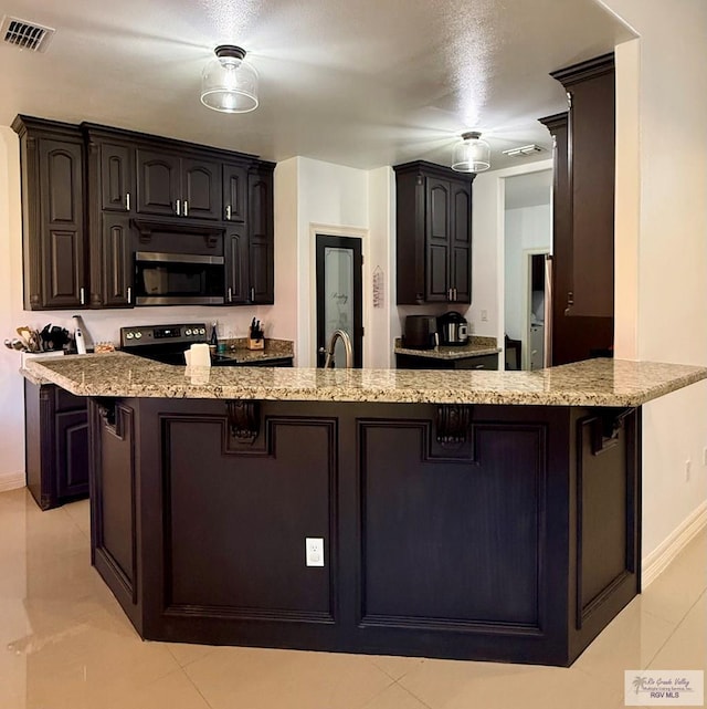 kitchen featuring light stone counters, visible vents, stainless steel microwave, electric range, and a peninsula