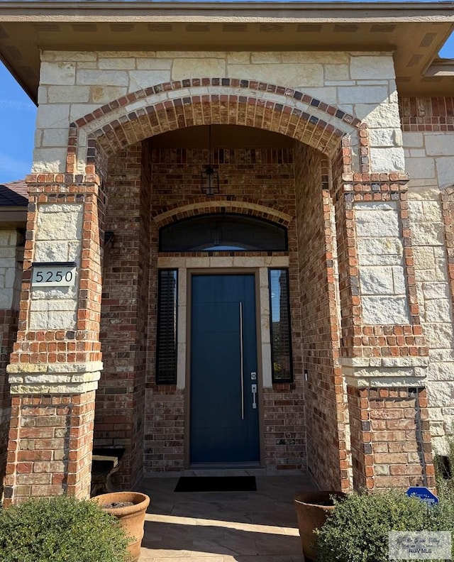 view of exterior entry featuring brick siding