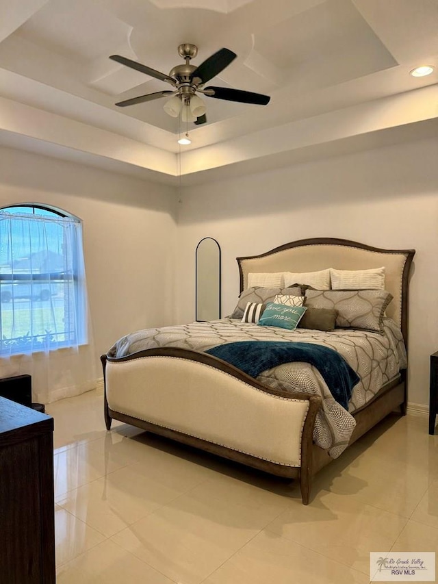 bedroom featuring light tile patterned flooring, recessed lighting, a ceiling fan, baseboards, and a tray ceiling