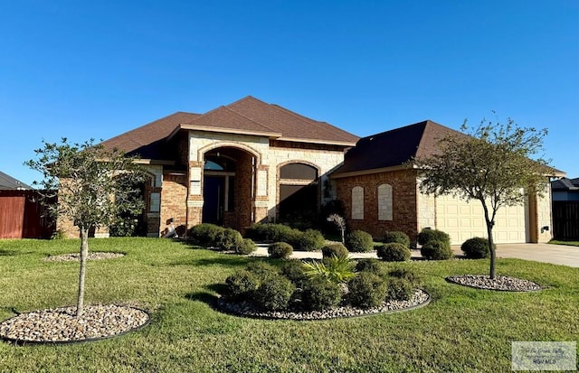 french country inspired facade with driveway, a garage, fence, a front lawn, and brick siding