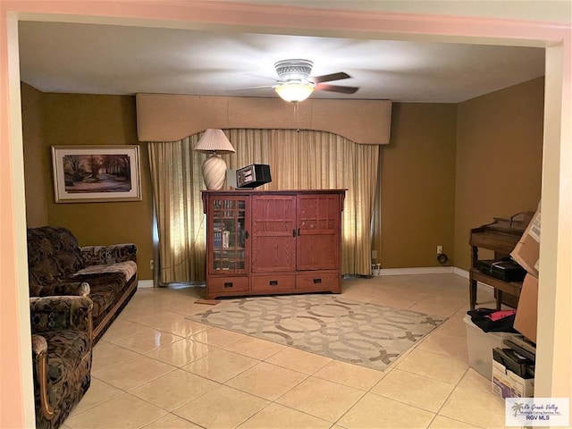 living area with light tile patterned floors and ceiling fan