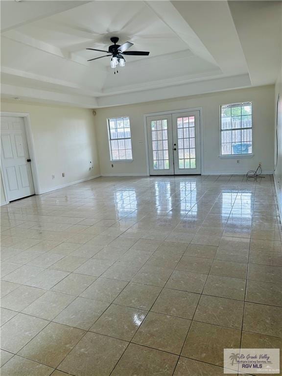 tiled empty room with french doors, a raised ceiling, ceiling fan, and a healthy amount of sunlight