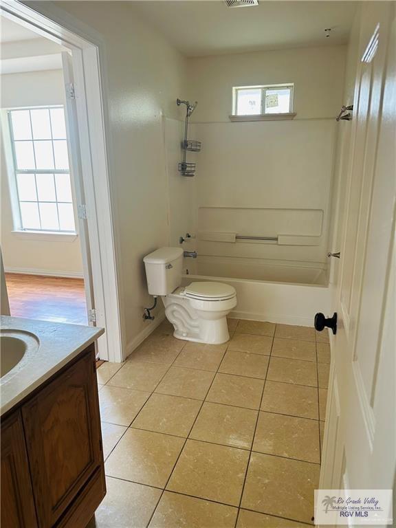 full bathroom with tile patterned flooring, vanity, a healthy amount of sunlight, and toilet