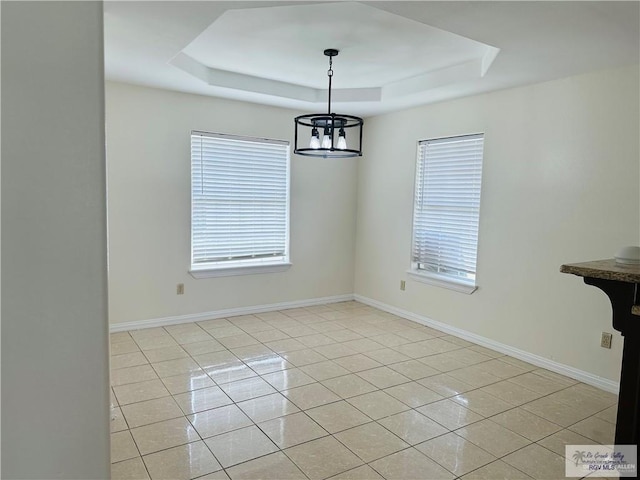 unfurnished dining area featuring a tray ceiling, light tile patterned floors, and a notable chandelier