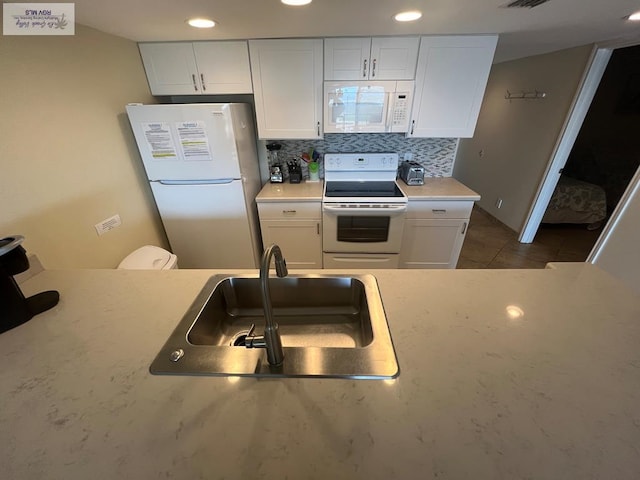 kitchen with white appliances, white cabinets, tile patterned floors, sink, and tasteful backsplash