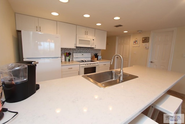 kitchen with white cabinets, a breakfast bar, white appliances, and sink