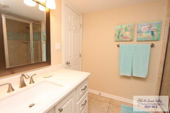 bathroom featuring tile patterned floors, vanity, and a shower with shower door