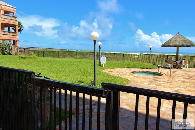 view of yard featuring a patio area, a community hot tub, and a water view