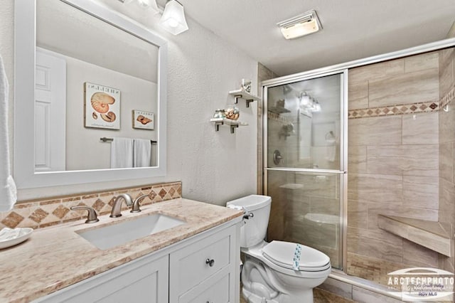 bathroom with vanity, toilet, a shower with door, and decorative backsplash