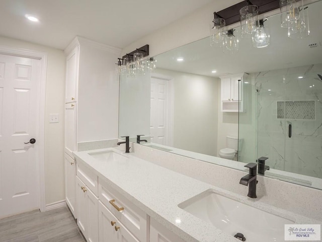 bathroom featuring vanity, hardwood / wood-style flooring, a shower with door, and toilet