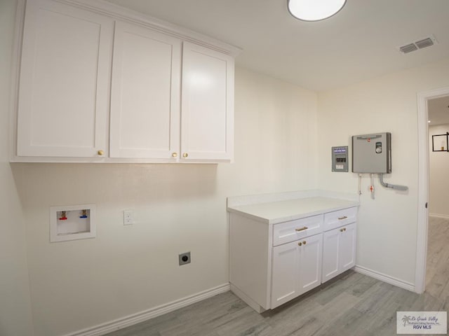 washroom featuring cabinets, electric dryer hookup, washer hookup, and light hardwood / wood-style flooring