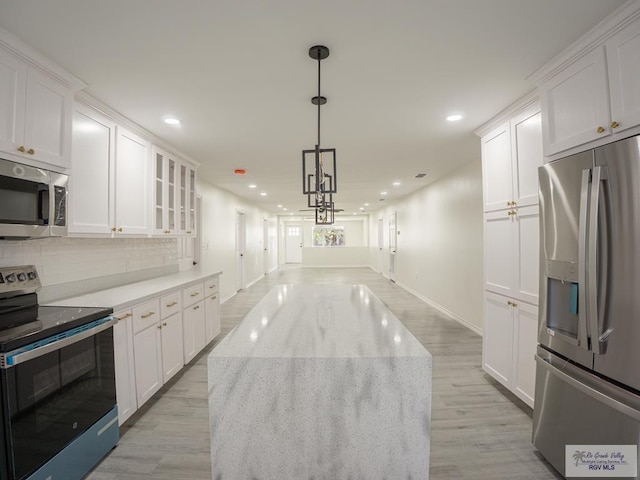 kitchen featuring hanging light fixtures, stainless steel appliances, white cabinets, and a kitchen island