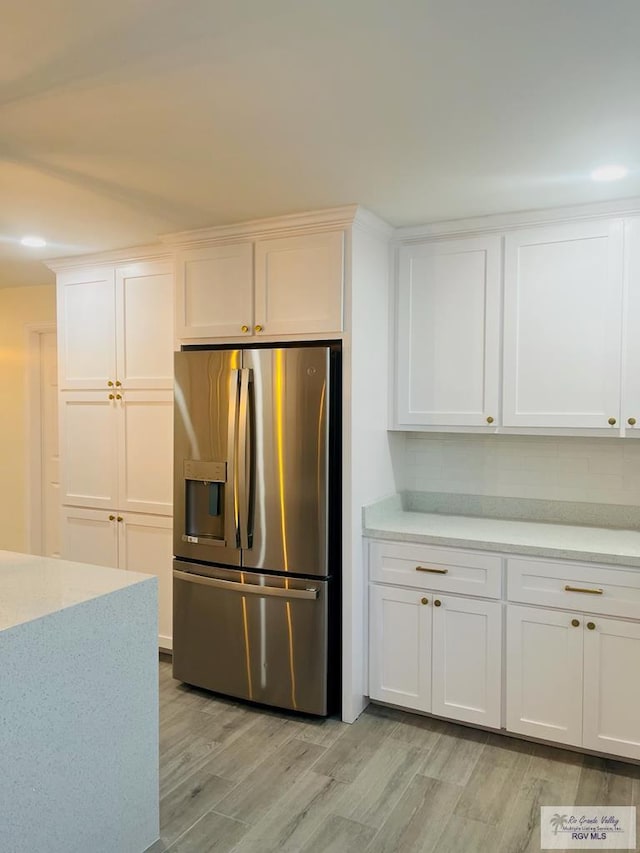 kitchen featuring light wood-type flooring, stainless steel fridge with ice dispenser, decorative backsplash, and white cabinets