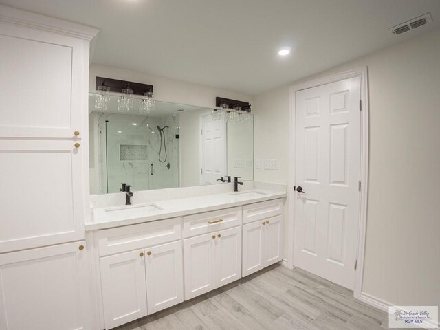 bathroom featuring vanity, wood-type flooring, and a shower with door